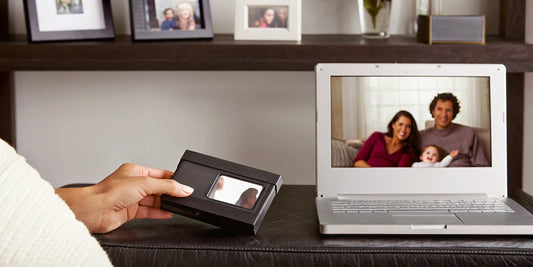 Hand holding a MiniDV tape, converting the old video to a digital file on a laptop.