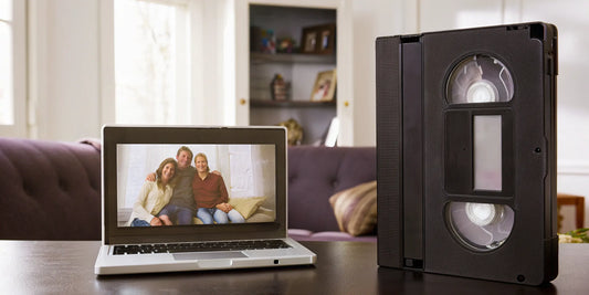 VHS-C tape next to a laptop displaying family photos.