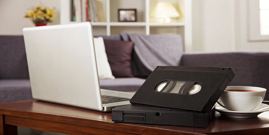 A stack of VHS tapes being converted to MP4 format on a laptop.