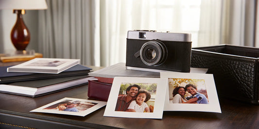 A vintage camera and a collection of polaroids on a desk, ready to be scanned.