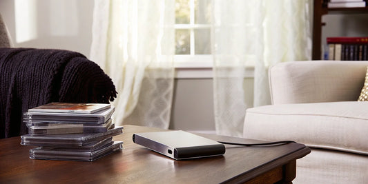 A stack of CDs and a USB drive prepared for a CD to USB transfer.