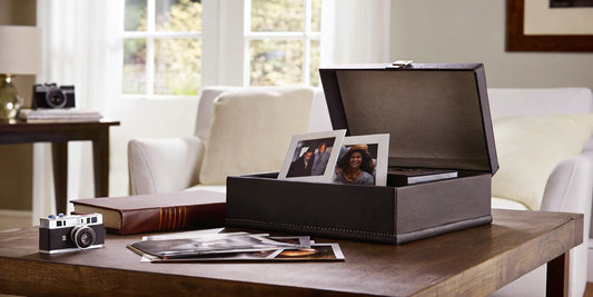 A box of old photos and a vintage camera on a table, ready to scan photos near me.