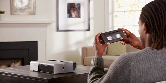 A person holding a DV tape, ready to digitize and preserve home movies with a player.
