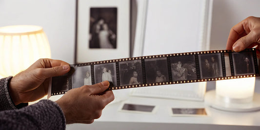 A person holds a strip of 35mm negatives, preparing to scan them.