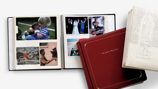 Open family photo albums with printed pictures stacked on a white background